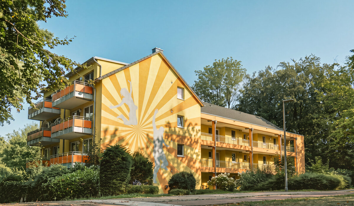 Gelbes Haus mit Malerei und Balkonen im Grünen.