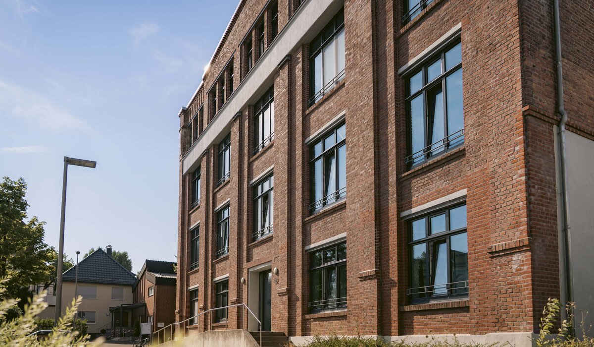 Fassade des Gebäudes Walther-Rathenau-Straße 56–58 mit Ziegelsteinoptik und großen Fenstern.
