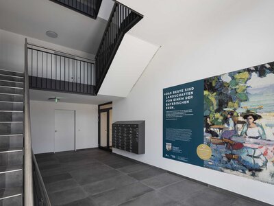 Moderner Eingangsbereich mit Treppe, Briefkästen und Kunstwerk an der Wand.