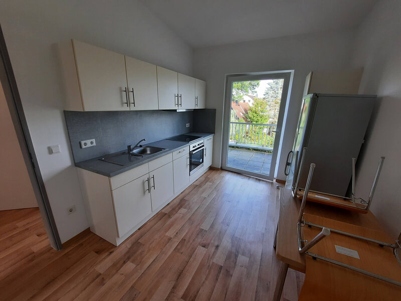 Moderne Küche mit Arbeitsfläche, Herd, Kühlschrank und Fenster zur Terrasse.