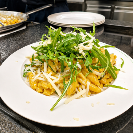 Hausgemachte Pasta mit Ruccola-Topping angerichtet auf einem Teller. 