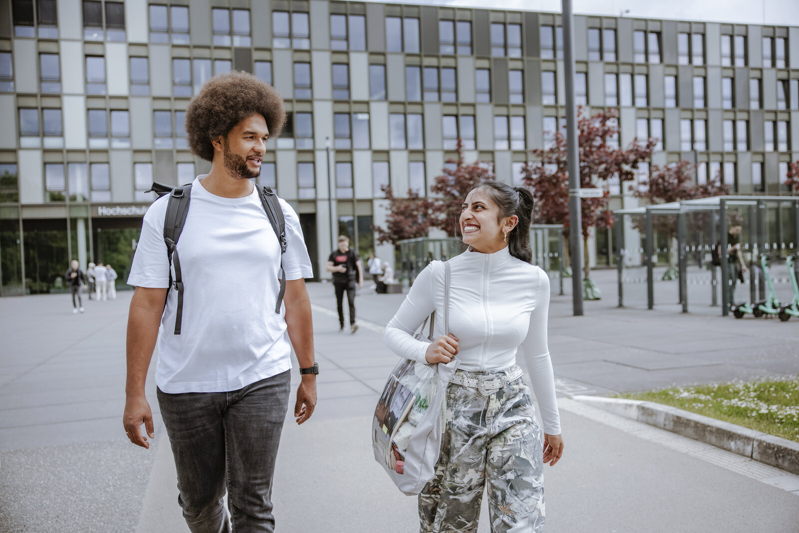 Zwei junge Menschen in Freizeitkleidung beim Spazieren auf dem Campus Bielefeld..