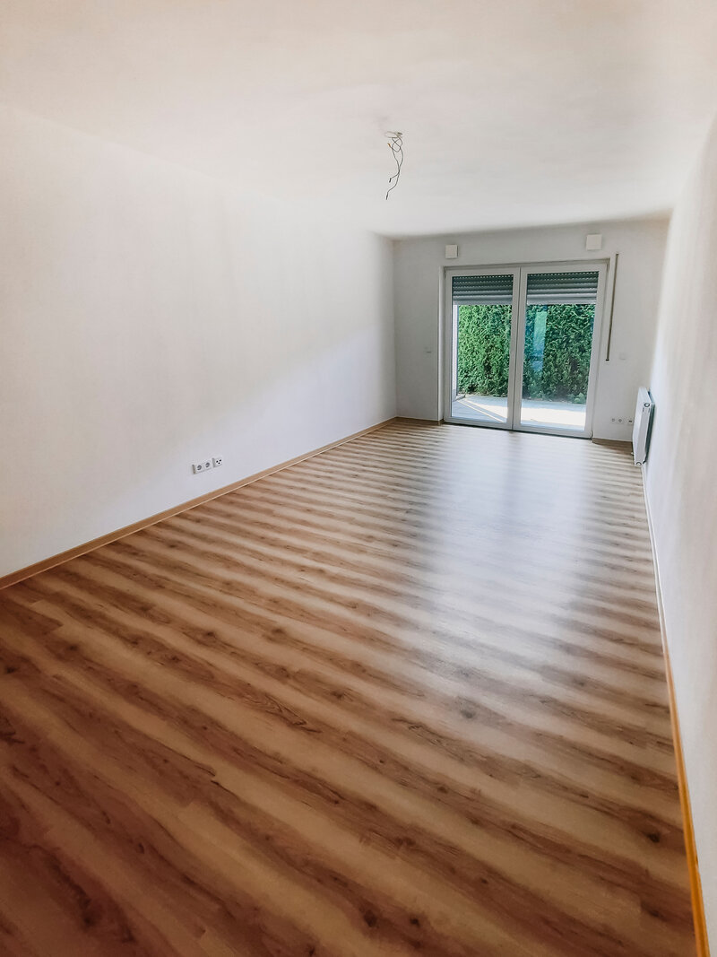 Leeres 2er-WG Zimmer mit Holzboden und Zugang zum Balkon