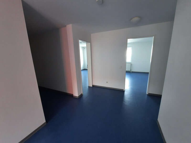 Blick in die 3er-WG mit blauen Böden, hellen Wänden und mehreren Räumen, die ins Licht führen.