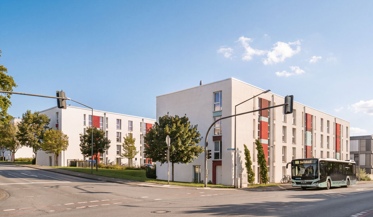 Fassade des Gebäudes Gutenbergstraße 1/13 mit bunten Akzenten und Bus.