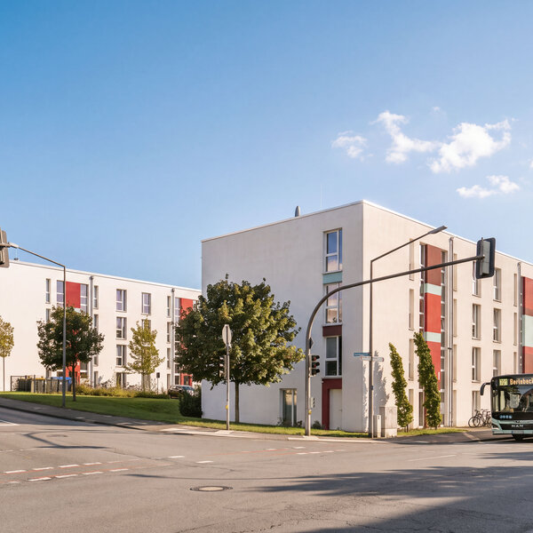 Fassade des Gebäudes Gutenbergstraße 1/13 mit bunten Akzenten und Bus.