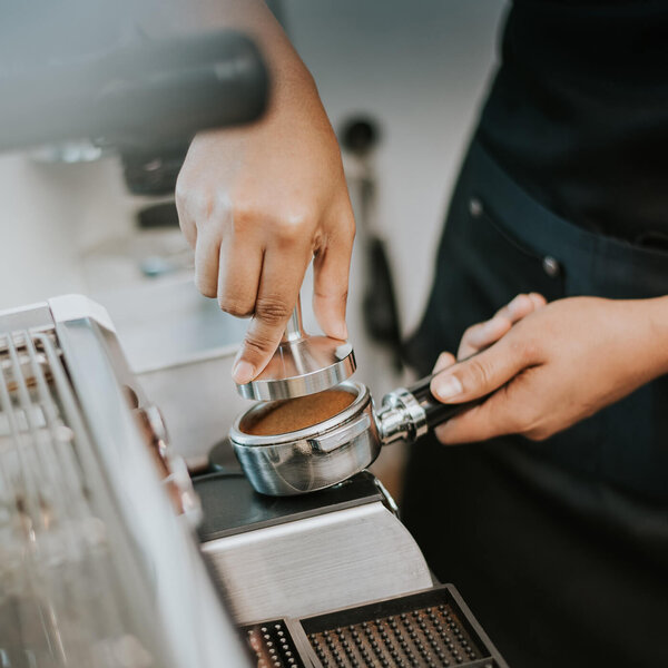 -Barista bereitet Kaffee vor mit einer Siebträgerportafilter und einer Espressomaschine.