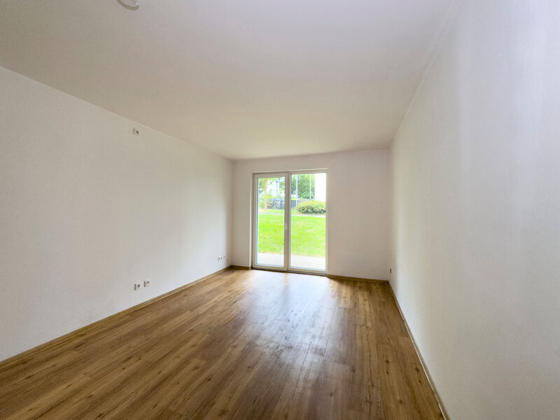 Modernes leeres 2er-WG-Zimmer mit Holzboden und Zugang zur Terrasse bzw. zum Balkon.