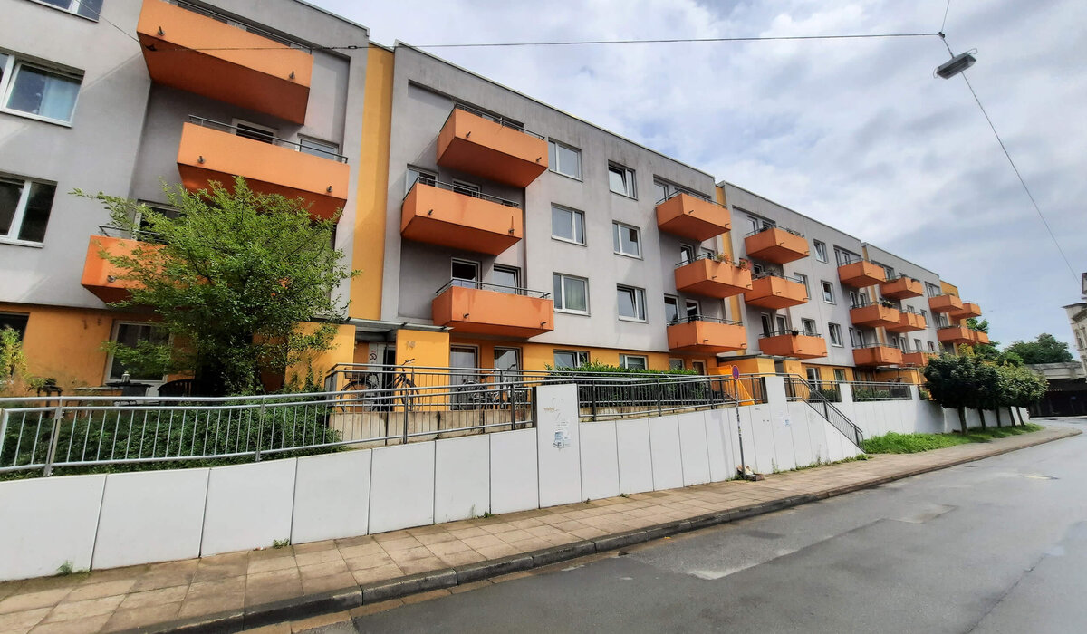 Wohnanlage Arndtstraße 12–18: moderne Wohnungen mit orangefarbenen Balkonen und Vorgarten.