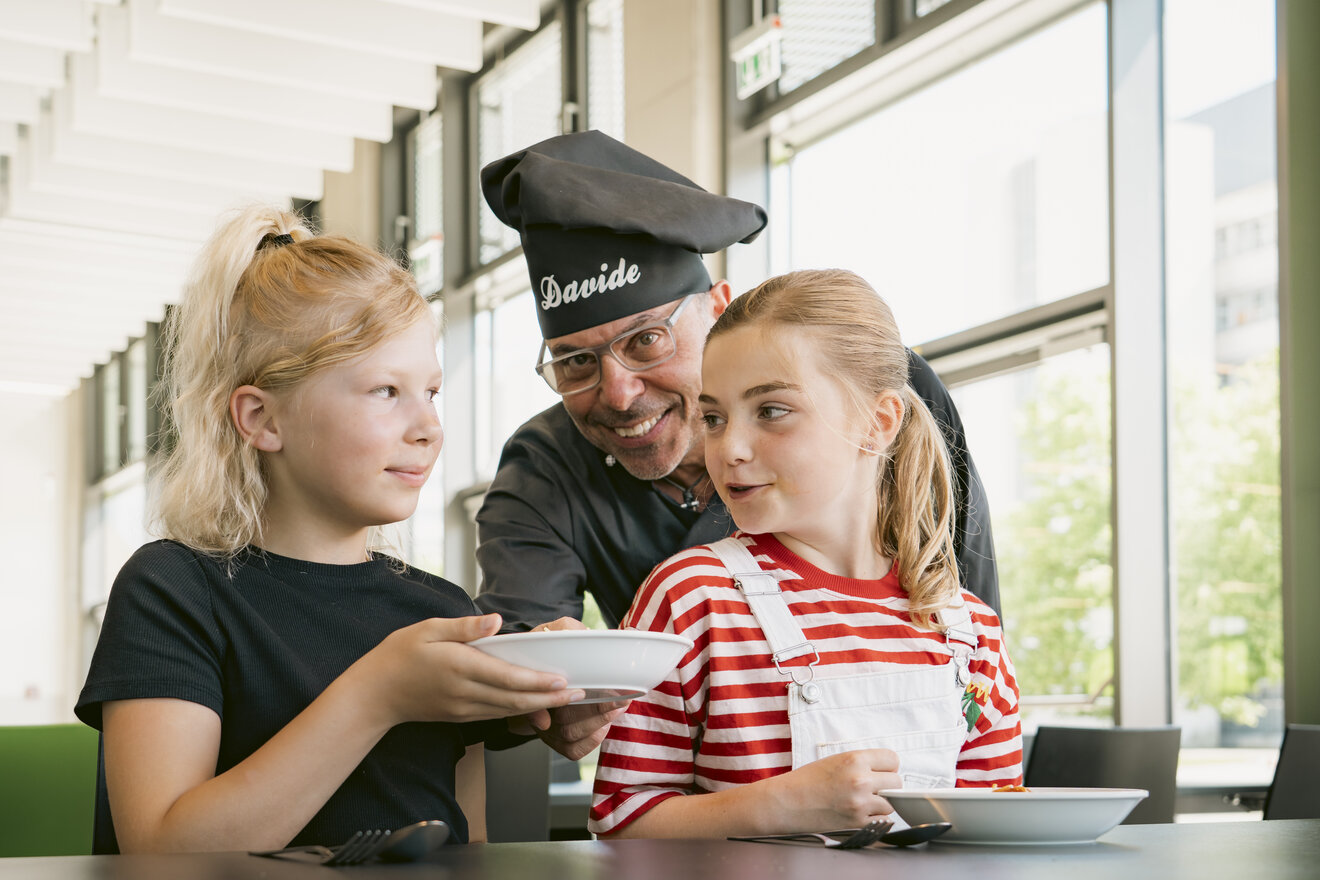 Koch reicht Kindern Tellergericht 