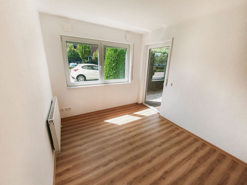 Leeres 4er-WG Zimmer mit Holzboden und Zugang zum Balkon