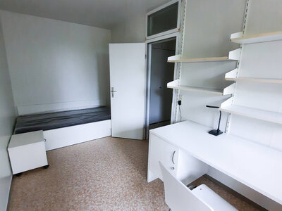 Helles Zimmer mit Bett, Schreibtisch, Stuhl und Regalen für Stauraum.