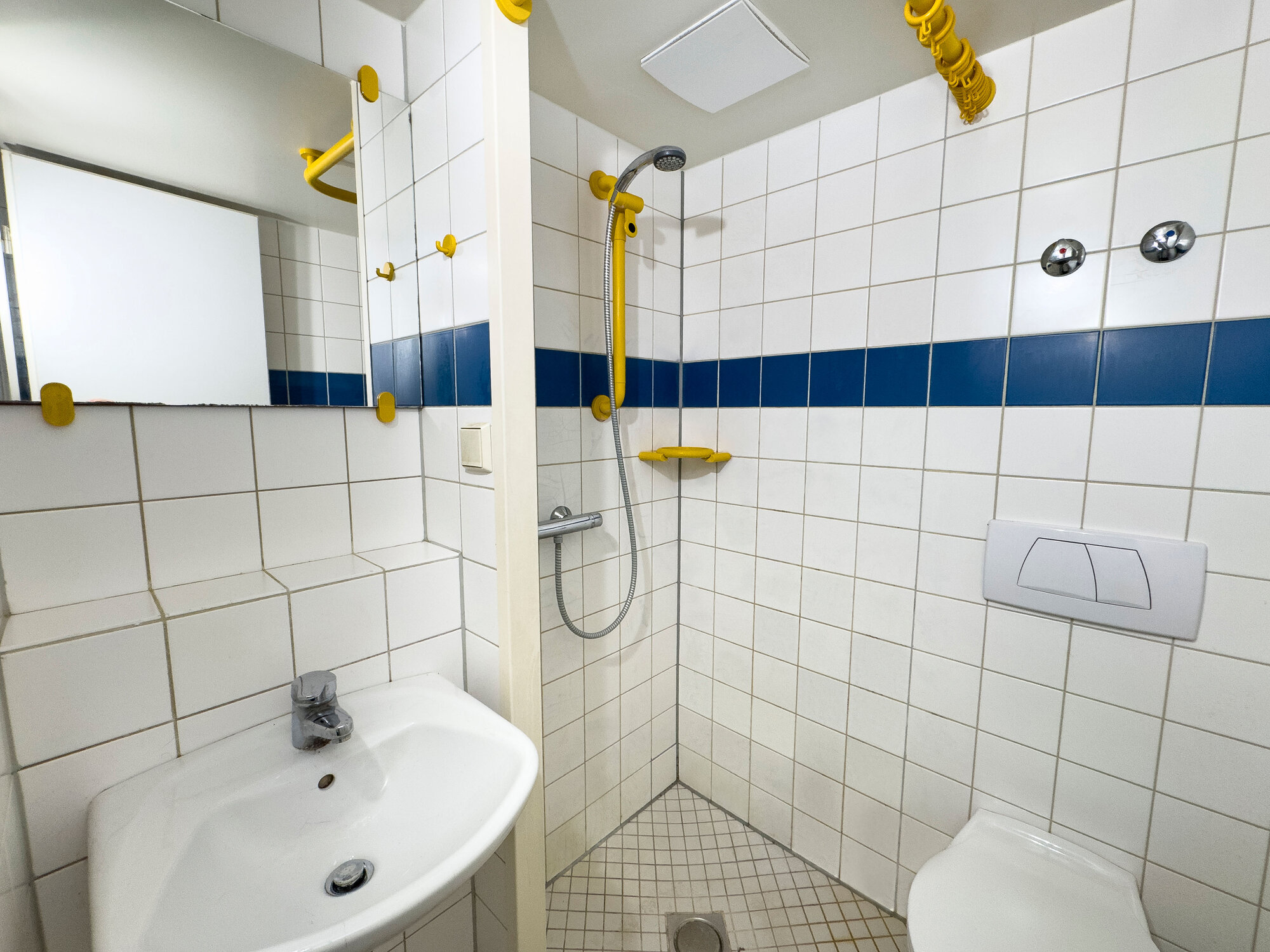 Gefliestes Badezimmer mit bodentiefer Dusche und Spiegel