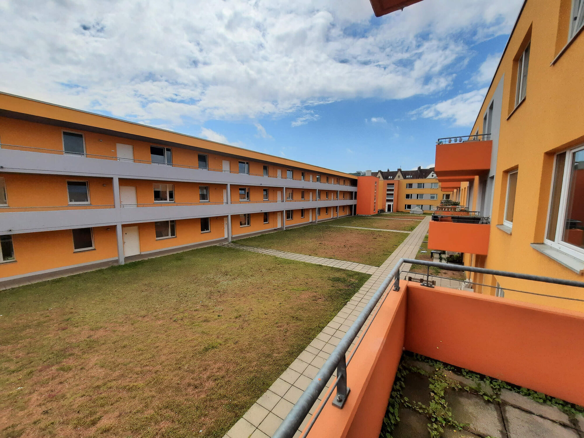 Blick auf Innenhof der Wohnanlage Arndtstraße 12–18 mit orangenem Anstrich und gepflasterten Wegen.