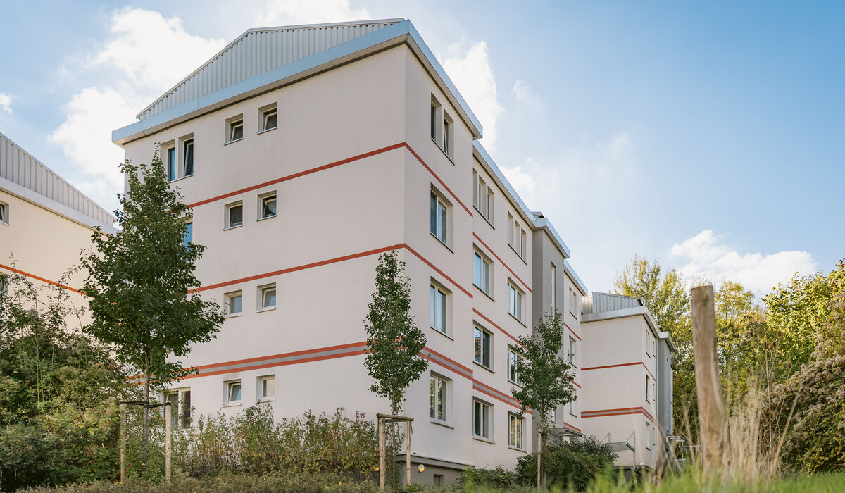Moderne Wohnanlage "Morgenbreede 17-23" mit mehreren Häusern, grüner Umgebung und blauem Himmel im Hintergrund.