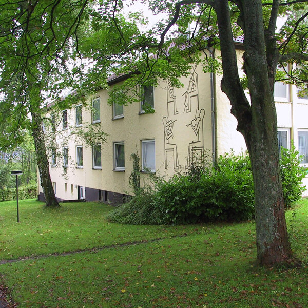 Fassade der Mozartstraße 17 mit grüner Umgebung und künstlerischem Wanddesign.