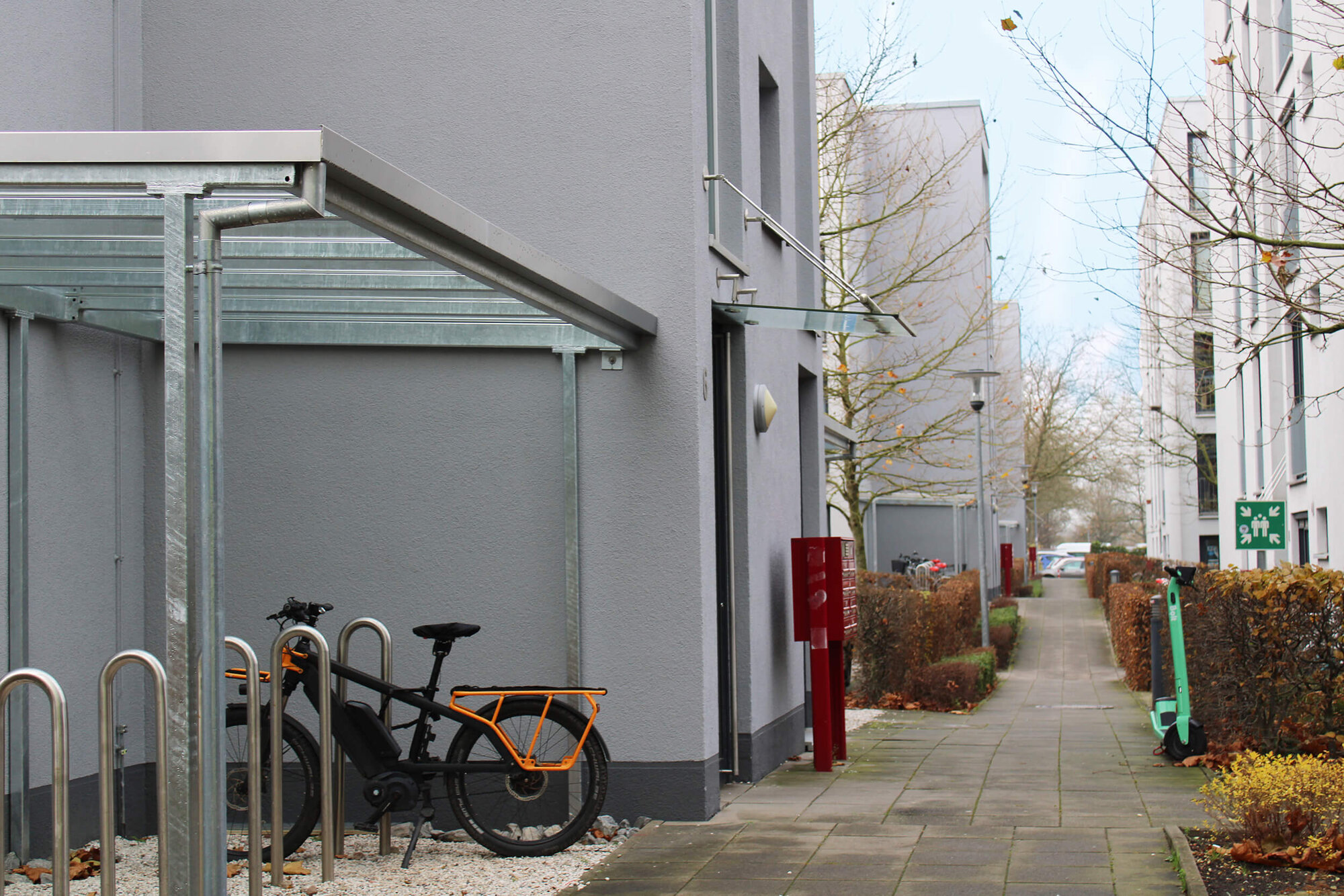 Fahrradständer mit einem schwarzen E-Bike und orangefarbener Rahmen bei einem modernen Gebäude.