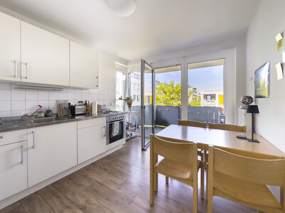 Helle WG-Küche mit großem Tisch und vier Stühlen mit Zugang zum Balkon