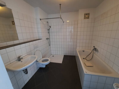Badezimmer mit Dusche, Badewanne, WC und Waschbecken, gefliest in Weiß und Schwarz.