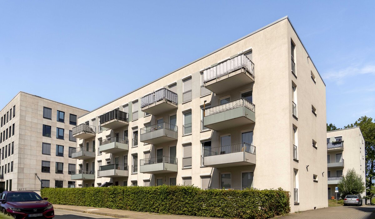 Fassade des Wohngebäudes Am Hallenbad 3–9 mit Balkonen und modernen Fenstern.