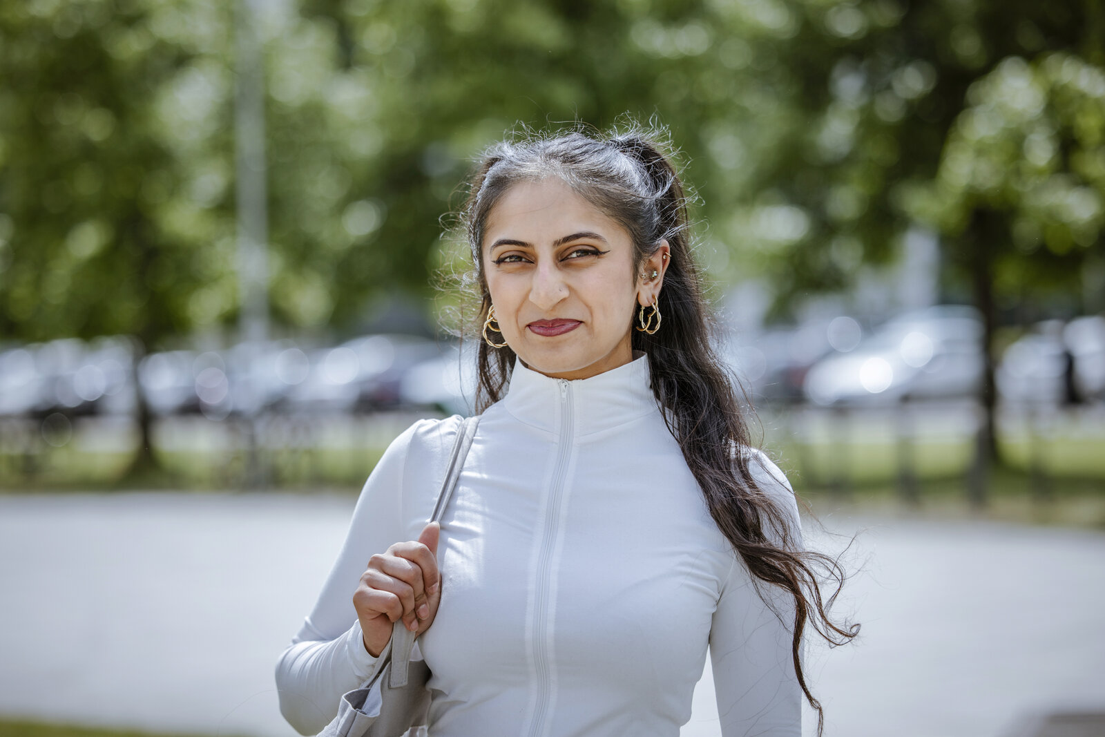 Eine junge Frau steht auf dem Campus Bielefeld und lächelt in die Kamera.