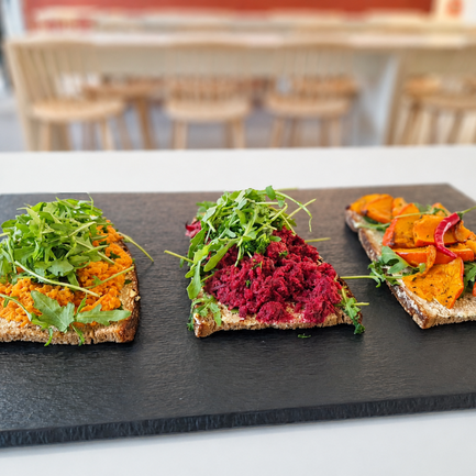 Brote mit veganen Aufstrichen auf einer Schieferplatte.