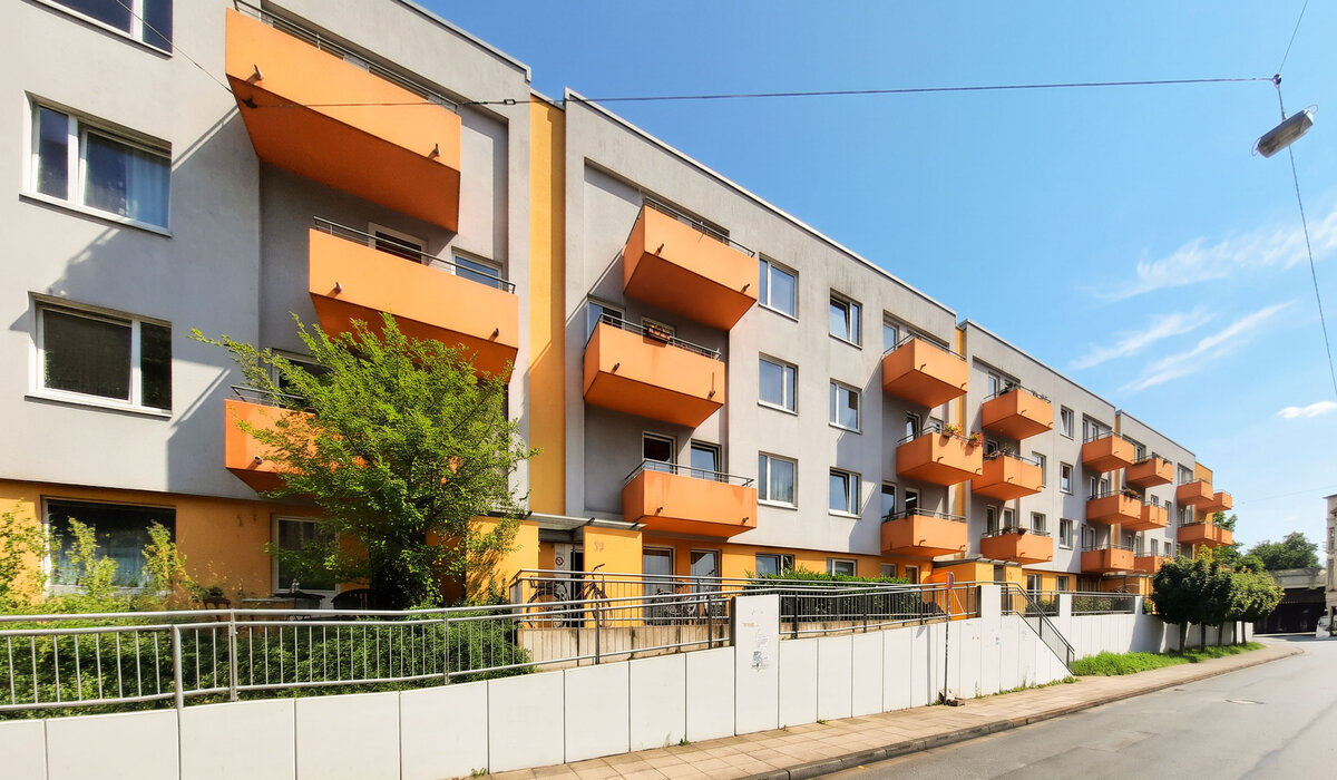 Wohnanlage Arndtstraße 12–18: moderne Wohnungen mit orangefarbenen Balkonen und Vorgarten.